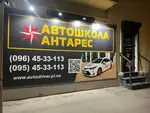Вхід до філії автошколи «Антарес» у Полтаві на вул. Соборності, 62 з великим вечірнім банером, підсвіткою, номерами телефонів та QR-кодом для запису на курси водіння.